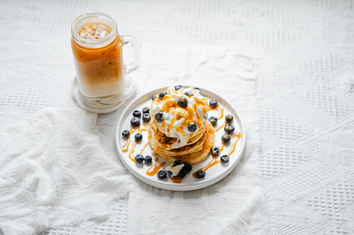 Pancakes with whipped cream and blueberries on a white background