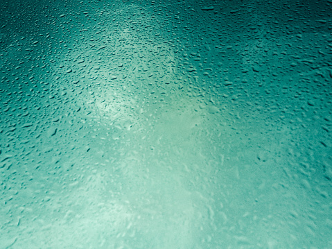raindrops and on a fogged window pane with greenish background light