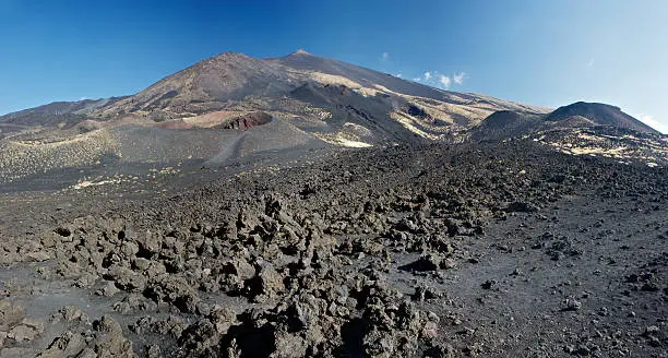 Close shot of a lavaflow of the Mt. Etna's parasite crater. Mt. Etna's peak in the background