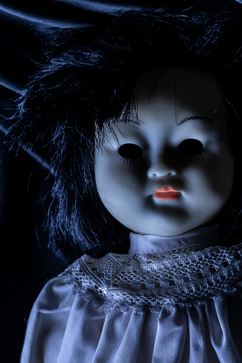 A cl;ose up of a creepy vintage baby doll with blacked out eyes.