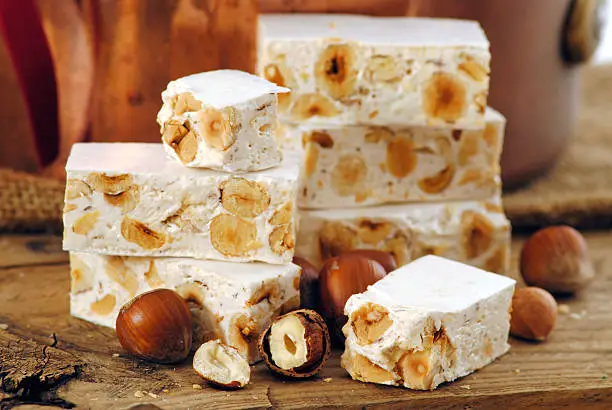 Typical italian nougat on rustic wood table with nuts