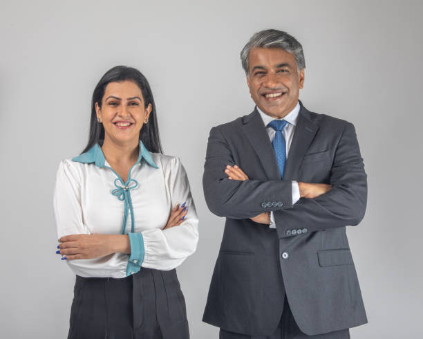 istock Smiling colleagues with arms crossed standing on white background 1587466458