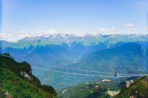 man walking on rope suspension bridge in caucasus mountains, Russia. High quality photo