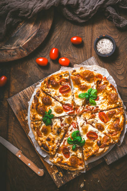 istock Whole tomato quiche with basil on wooden background 1587488113