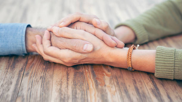 istock Two people holding hands with compassion and love 1587488131
