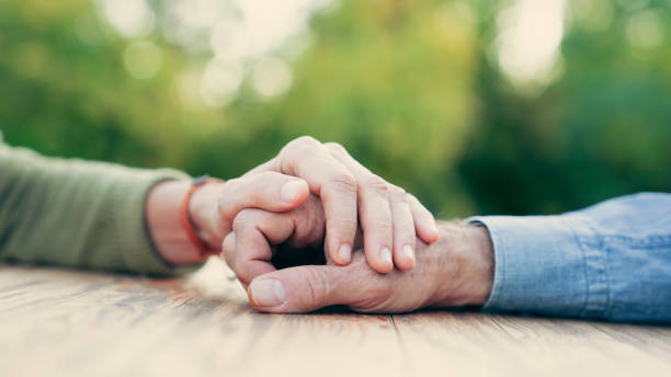 due persone che si tengono per mano con compassione e amore - consolare immagine foto e immagini stock