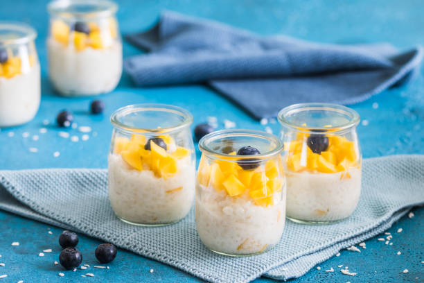 istock Coconut rice pudding with mango in dessert glasses on blue background 1587489758