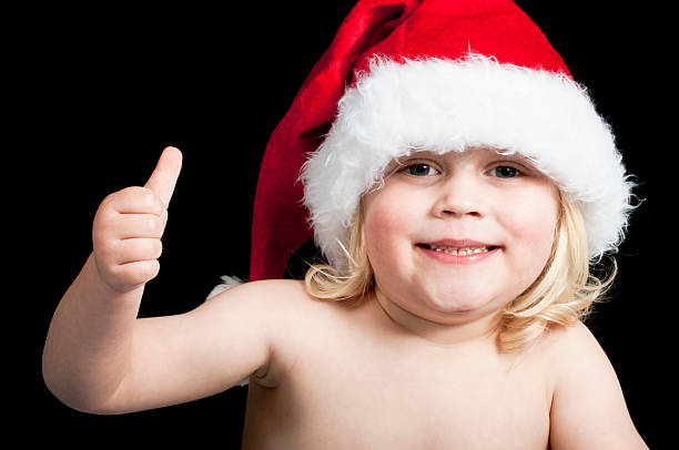 Baby wearing a santa hat a happy christmas baby wearing a santa hat with his thumb up lieke klaus stock pictures, royalty-free photos & images