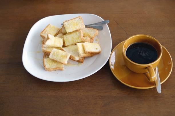 istock Toast bread with black coffee on wooden table in the cafe. 1587519768