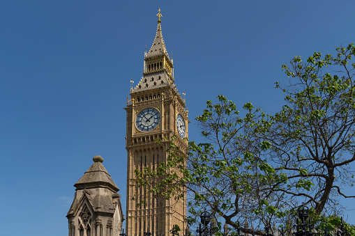 Famous Big Ben against clock tower located on street of London against blue sky