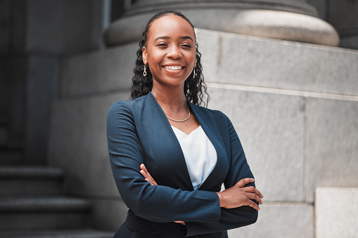 Arms crossed, attorney or portrait of happy black woman with smile or confidence working in a law firm. Confidence, empowerment or proud African lawyer with leadership or vision for legal agency