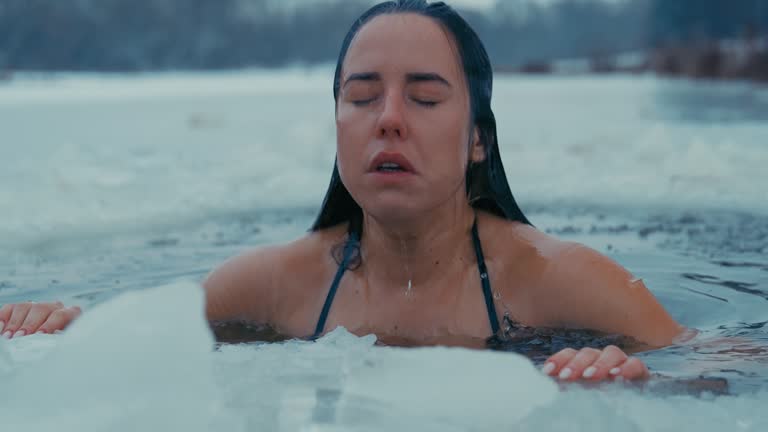 Woman  with long hair going winter swimming at freezing temperature. Diving under water