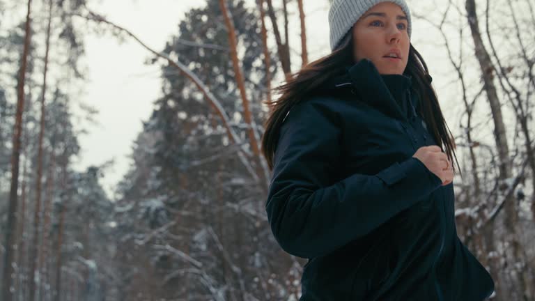 Winter exercise. Woman living an active lifestyle running through a white winter forest