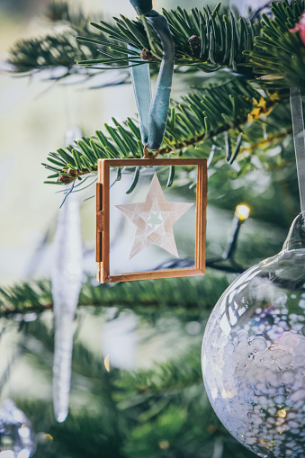 Beautiful Origami 5-pointed star in glass frame ornament hanging on Christmas tree