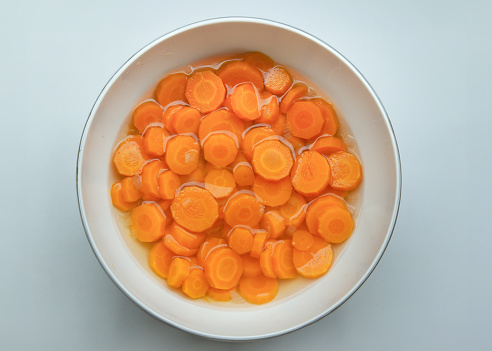 Carrots cooked in slices in a porcelain bowl from above