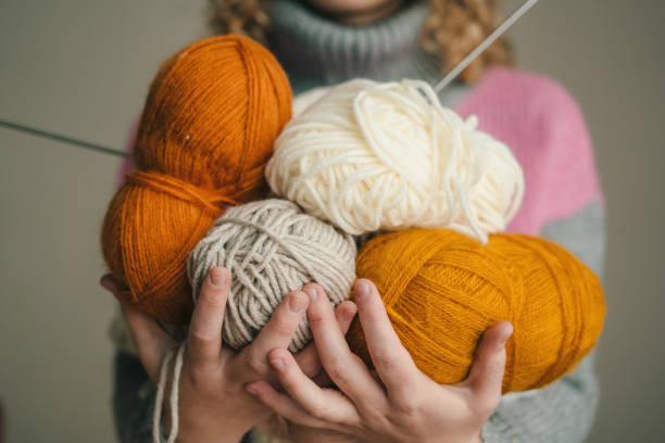 istock Woman's hands holding multi-colored balls of wool yarn. Minimalistic creative medicine concept 1587599846