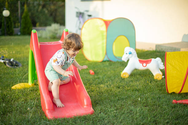 istock Baby boy sliding at backyard playground 1587603183