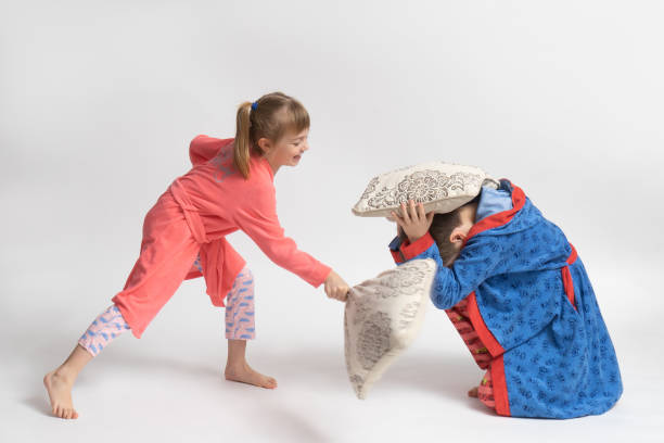 дети в пижамах устроили бой подушками на белом фоне - battle dress стоковые фото и изображения