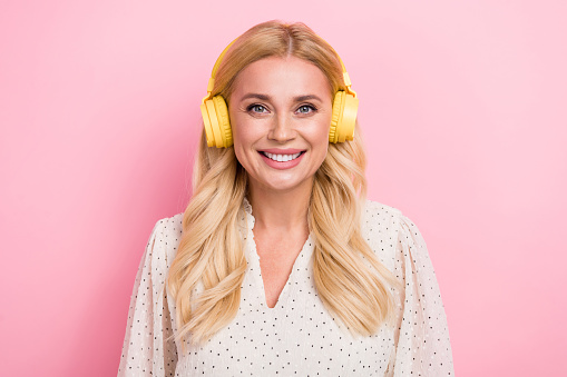 Portrait photo of friendly young lady listen her new stylish yellow earphones spotify album playlist isolated on pink color background.