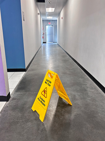 Wet floor warning sign in a concrete corridor