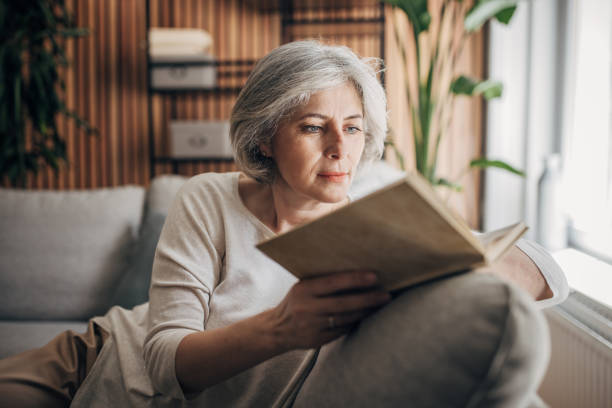 istock Mature woman reading at home 1587696639