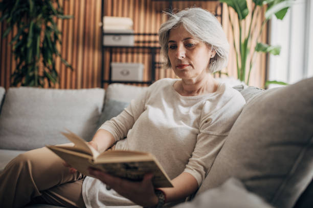 istock Mature woman reading at home 1587697691