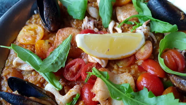 Paella seafood Spanish food rice baked with mussle squid fish and shrimp topping with tomato and lemon 4k