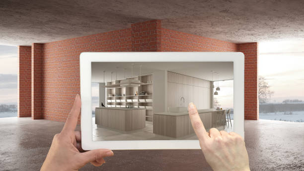 istock Augmented reality concept. Hand holding tablet with AR application used to simulate furniture and design products in interior construction site, modern white kitchen with island 1587710586