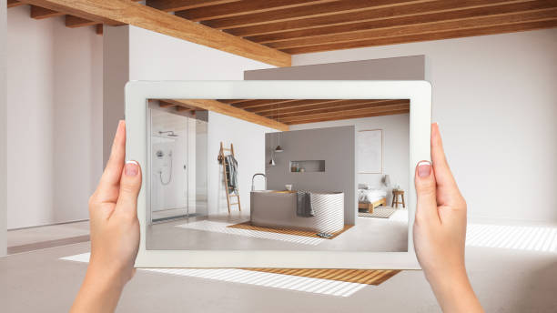 istock Augmented reality concept. Hand holding tablet with AR application used to simulate furniture and design products in empty wooden interior, japandi minimal bedroom and bathroom 1587715490