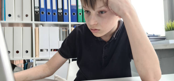 istock Frustrated sad schoolboy looking at laptop closeup 1587720779