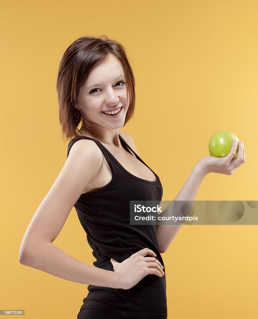 Adolescente sonriente sosteniendo una manzana verde - Foto de stock de 14-15 años libre de derechos