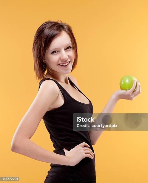 Adolescente Sonriente Sosteniendo Una Manzana Verde Foto de stock y más banco de imágenes de 14-15 años