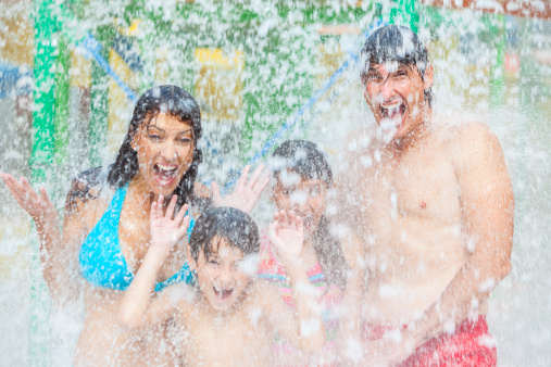 A happy family of mother, father and children, son and daughter, having fun on vacation at a water park