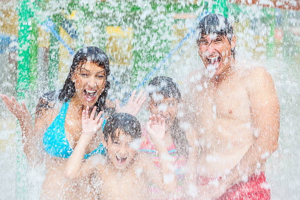 Mother Father Son Daughter Child Family Water Park A happy family of mother, father and children, son and daughter, having fun on vacation at a water park one piece swimsuit photos stock pictures, royalty-free photos & images