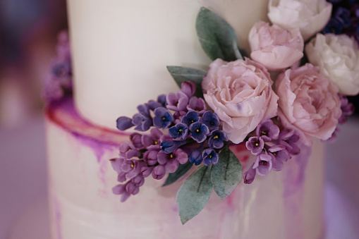 Close-up of a beautiful and delicious festive wedding cake decorated with rose flowers. The concept of preparing for the wedding.