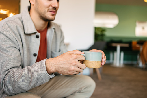 A man holding a cup of coffee or tea at work. Taking a break