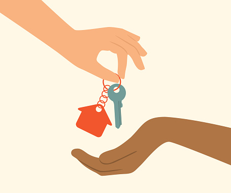 One hand gives house key to the other hand. Real estate concept