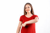 Smiling lovely girl points finger down, shows advertisement on blank white space. Young brunette female looking happy by promotion offer, stands over white background