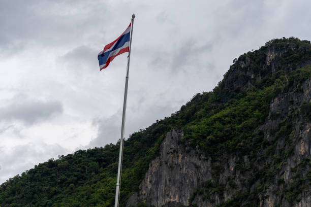 istock Thai flag pole in forest and mountains and blue sky 1587785913