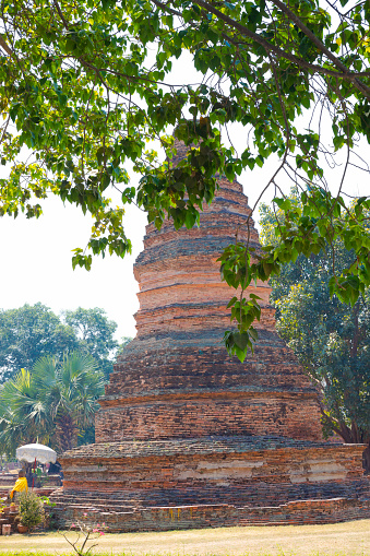 Thai buddha and old pagodas at Wat Wiang Tha Kan grounds seen from behind trees,  a thousand year old historical site in south of Chiang Mai
