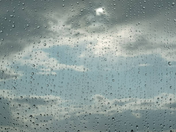 View from the window during the rain on the clouds illuminated by the sun. Raindrops on glass