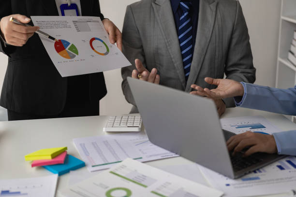 istock Business meetings using computers, laptops, calculators, notebooks, paper stock market charts for quality improvement plan analysis, brainstorming, collaborating in the office. 1587801426