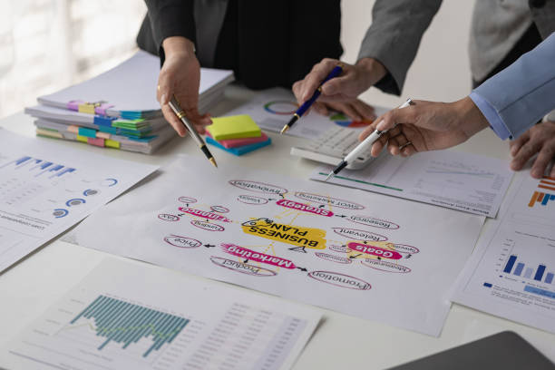 istock Business meetings using computers, laptops, calculators, notebooks, paper stock market charts for quality improvement plan analysis, brainstorming, collaborating in the office. 1587801431