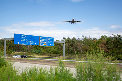 Landing airplane - traffic on German highway A5 nearby Frankfurter Kreuz. Low angle view