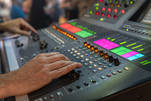 Sound technician hands controlling a digital audio mixing console. Selective focus. Close-up of a modern electric sound mixing console during a concert.