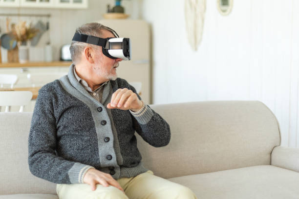 istock Excited mature senior man wearing using virtual reality metaverse VR glasses headset at home. Grandfather touching air during VR experience on virtual reality helmet. Simulation hi-tech videogame. 1587807625