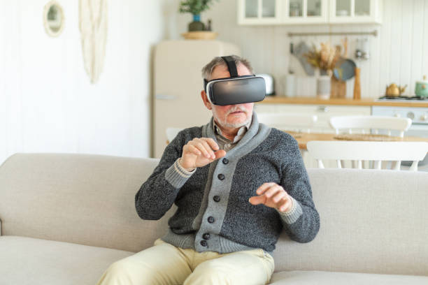istock Excited mature senior man wearing using virtual reality metaverse VR glasses headset at home. Grandfather touching air during VR experience on virtual reality helmet. Simulation hi-tech videogame. 1587807665