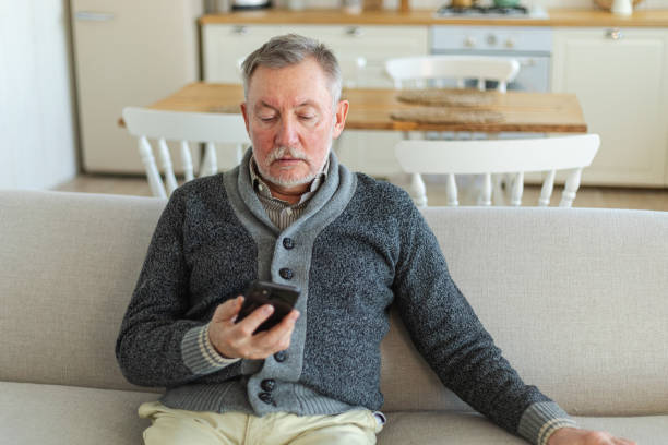 istock Happy middle aged senior man holding using smartphone touch screen typing scroll page. Stylish older mature beard grandfather with cell phone using internet social media apps at home. Shopping online. 1587807861