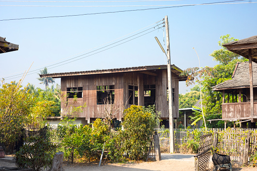 Old weathered wooden thai stilt houses and town houses  near On Tai, Chiang Mai, San Kamphaeng district of Chiang Mai. Trees and bushes are around buildings