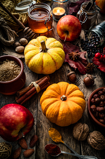 Autumn decorative pumpkins with apples, spices, nuts and fall leaves on dark background. Thanksgiving or Halloween holiday